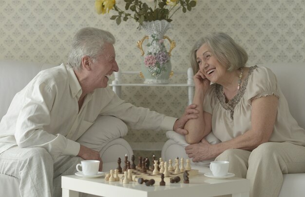 Szczęśliwa para seniorów odpoczywa w domu i gra w szachy