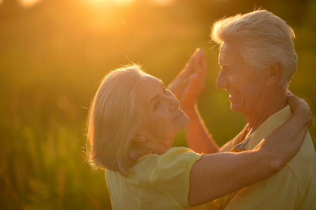 Szczęśliwa para seniorów uśmiecha się i tańczy na zewnątrz