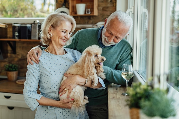 Szczęśliwa para seniorów z przyjemnością spędzania czasu z psem w domu
