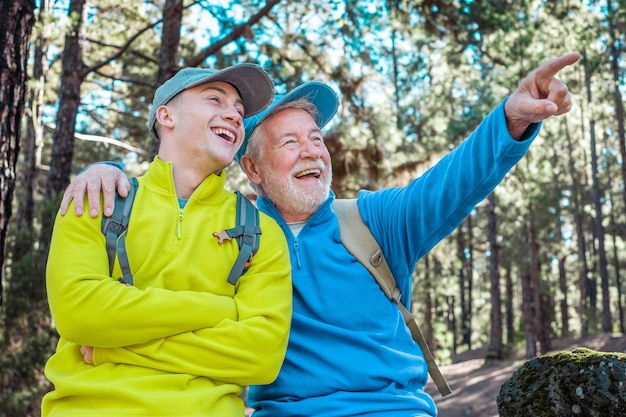 Szczęśliwa para starszego dziadka i młodego wnuka wędrujących razem po lesie, dzielących tę samą pasję do przyrody i zdrowego stylu życia