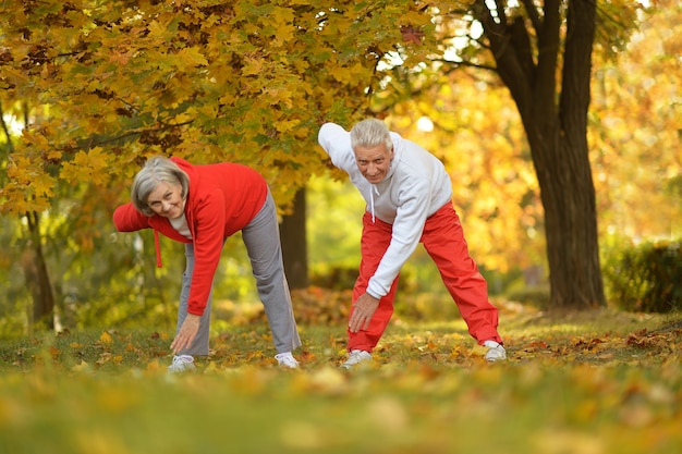Szczęśliwa para starszych ćwiczących w jesiennym parku