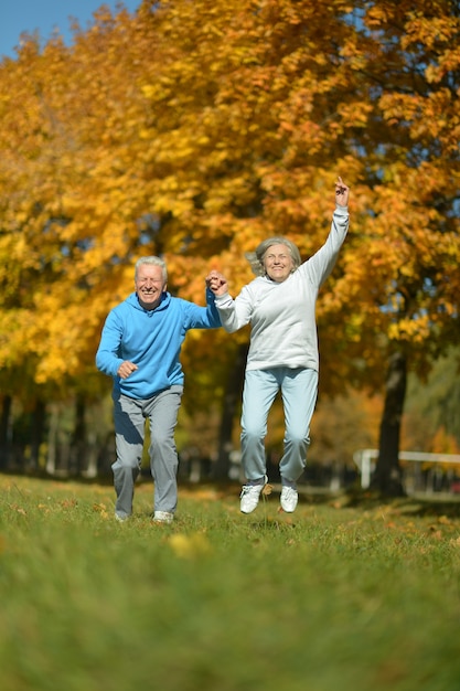 Szczęśliwa para starszych skaczących w jesiennym parku