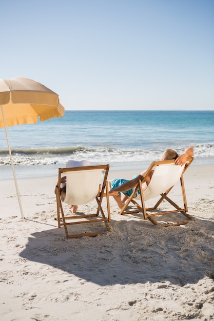 Szczęśliwa para sunbathing na ich leżakach