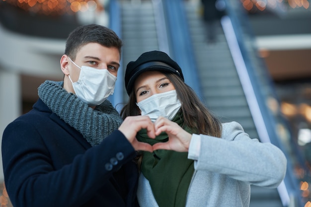 Szczęśliwa para świętująca Walentynki w maskach podczas pandemii covid-19 w mieście