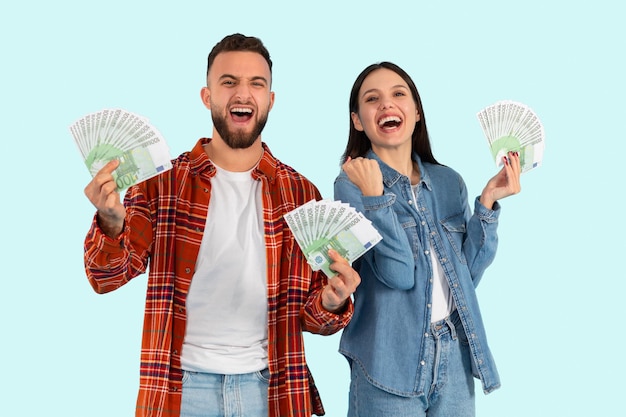 Zdjęcie szczęśliwa para trzymająca razem pieniądze na niebieskim tle