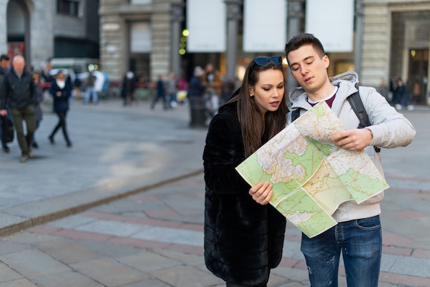 Szczęśliwa para turystów trzymających mapę w mieście