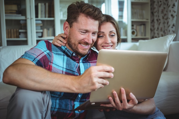 Szczęśliwa para używa laptop w żywym pokoju