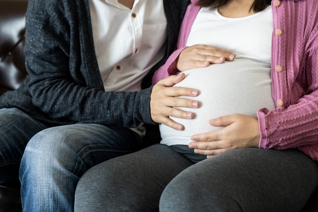 Szczęśliwa para w ciąży męża i żony. Młoda kobieta spodziewa się, że trzyma dziecko w ciąży brzuch.