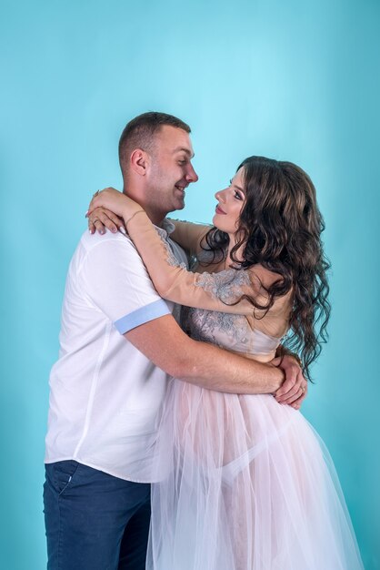 Szczęśliwa para w ciąży. Przystojny mąż przytulający swoją piękną żonę w studio