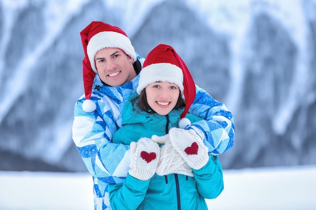 Szczęśliwa para w ciepłych rękawiczkach i czapkach Santa w snowy resort. Ferie zimowe