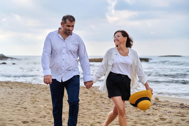 Szczęśliwa para w średnim wieku spacerująca razem po plaży