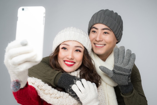 Szczęśliwa para w zimowych ubraniach robi zdjęcie smartfonem