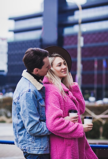 Szczęśliwa para z kawą podczas spaceru po mieście. Odkryty zdjęcie szczęśliwej pary młodych korzystających z randki