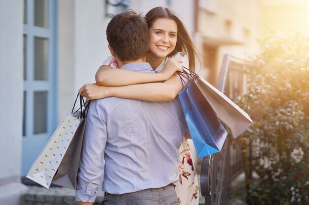 Szczęśliwa para z torby na zakupy po zakupach w mieście uśmiechając się i przytulając.