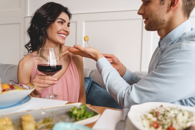 Szczęśliwa para zakochana siedzi przy stole z pysznym jedzeniem i winem w restauracji