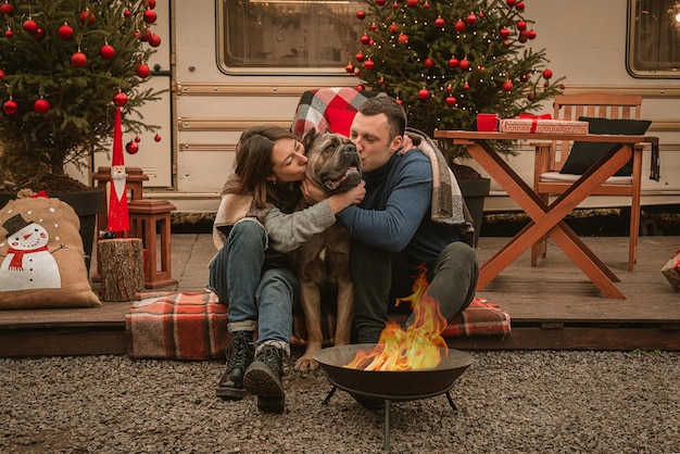 Szczęśliwa para zakochana wraz z psem spędzają razem czas na świętach Cane Corso i jego właściciele świętują Nowy Rok na świeżym powietrzu przy kamperze i przy ognisku