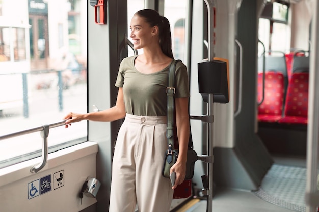 Zdjęcie szczęśliwa pasażerka stojąca w nowoczesnym tramwaju cieszy się wygodną przejażdżką