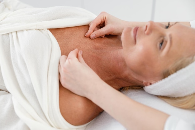 Zdjęcie szczęśliwa pewna siebie klientka otrzymuje masaż w procedurze spa gabinetu kosmetologa