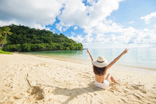 Szczęśliwa piękna kobieta w żółtym bikini ciesząca się i relaksująca na plaży