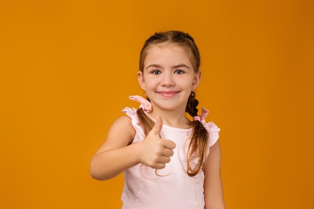 Szczęśliwa piękna mała dziewczynka w sukni pokazuje aprobaty