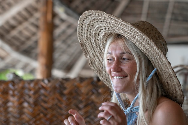 Szczęśliwa piękna młoda kobieta w słomkowym kapeluszu na tropikalnej plaży z bliska portret