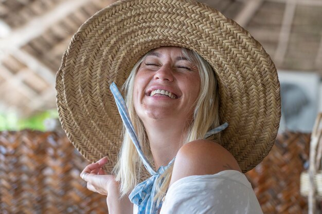 Szczęśliwa piękna młoda kobieta w słomkowym kapeluszu na tropikalnej plaży z bliska portret