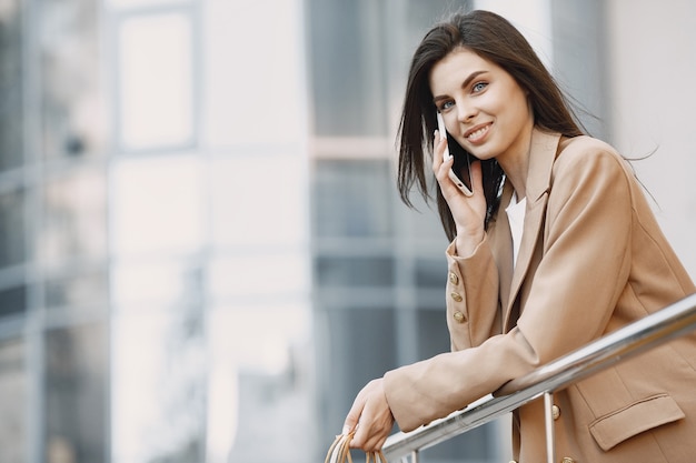 Szczęśliwa piękna młoda kobieta z torbami na zakupy, rozmawiająca przez telefon komórkowy w centrum handlowym