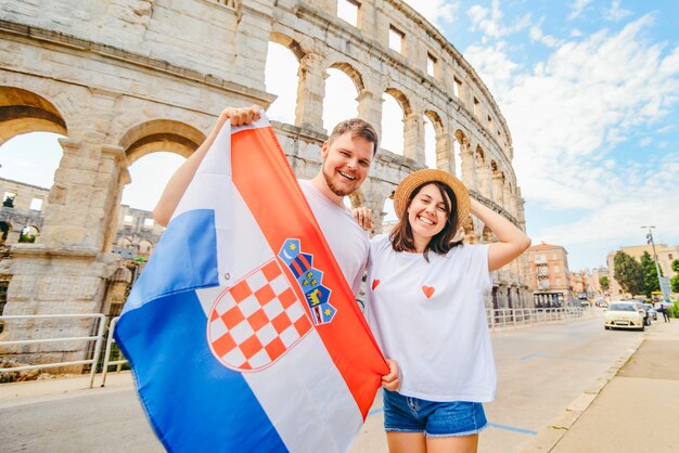 Szczęśliwa Piękna Para Przed Koloseum W Pula Chorwacja Z Chorwacką Flagą. Koncepcja Podróży