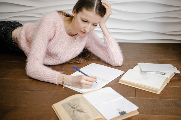 Zdjęcie szczęśliwa piękna studentka szkoły siedzi na podłodze