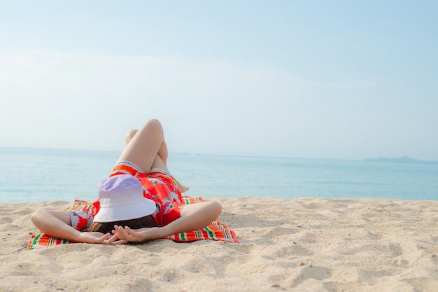 Szczęśliwa podróżniczka w czerwonej sukience cieszy się wakacjami na tropikalnej plaży