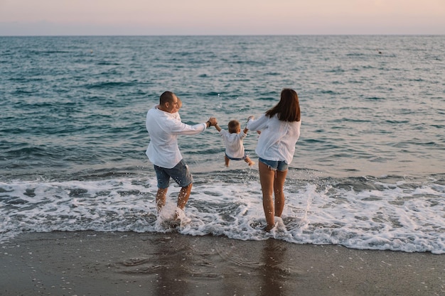 Szczęśliwa rodzina bawi się grając na plaży podczas wakacji na plaży Szczęśliwa rodzina i koncepcja wakacji Pejzaż morski o zachodzie słońca z pięknym niebem Rodzina na plaży