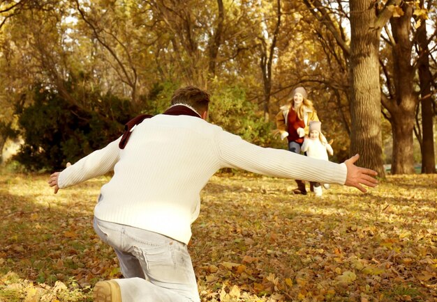 Szczęśliwa rodzina bawiąca się w pięknym jesiennym parku
