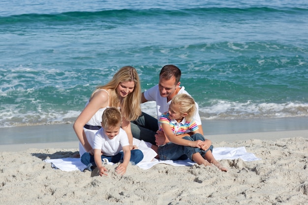 Szczęśliwa rodzina bawić się na piasku
