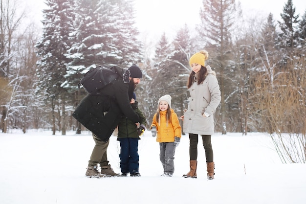 Szczęśliwa rodzina gra i śmieje się zimą na zewnątrz w śniegu. Zimowy dzień w parku miejskim.