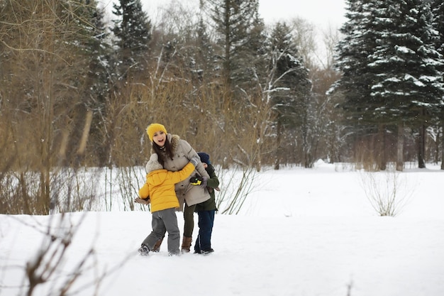 Szczęśliwa rodzina grając i śmiejąc się zimą na zewnątrz w śniegu. Zimowy dzień w parku miejskim.