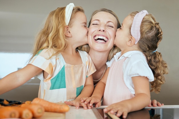 Szczęśliwa rodzina i młode dziewczyny całują mamę w radosną buzię świętując dzień matki w domu Siostry całują mamę w policzek w uroczej zabawnej zabawie świętując miłość i uczucie w kuchni