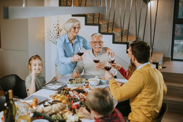 Szczęśliwa rodzina jedząca obiad z czerwonym winem w domu