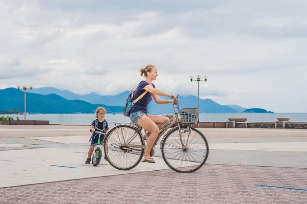 Szczęśliwa rodzina jeździ na rowerach na świeżym powietrzu i uśmiecha się. Mama na rowerze i syn na balancebike