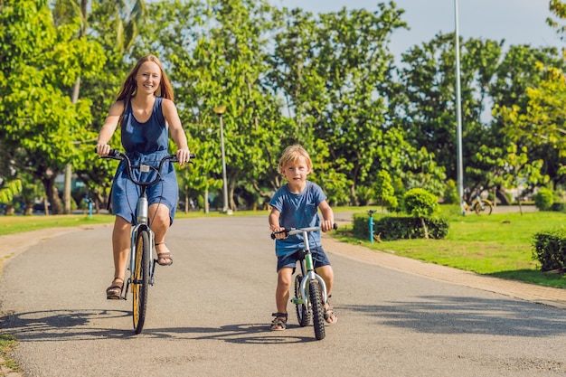 Szczęśliwa rodzina jeździ na rowerach na świeżym powietrzu i uśmiecha się. Mama na rowerze i syn na balancebike