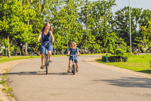 Szczęśliwa rodzina jeździ na rowerach na świeżym powietrzu i uśmiecha się. Mama na rowerze i syn na balancebike