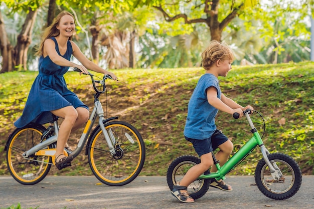 Szczęśliwa Rodzina Jeździ Na Rowerach Na świeżym Powietrzu I Uśmiecha Się. Mama Na Rowerze I Syn Na Balancebike