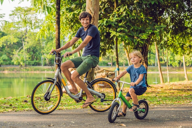 Szczęśliwa rodzina jeździ na rowerach na świeżym powietrzu i uśmiecha się. Ojciec na rowerze i syn na balancebike