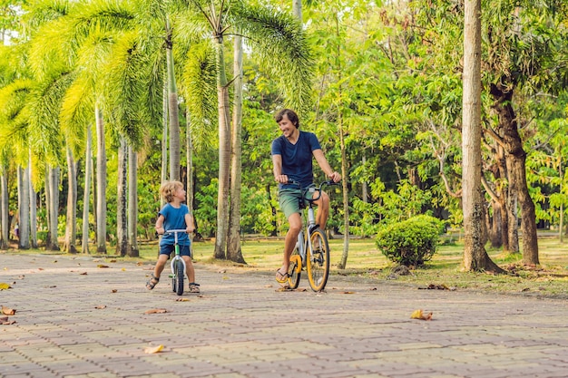 Szczęśliwa rodzina jeździ na rowerach na świeżym powietrzu i uśmiecha się. Ojciec na rowerze i syn na balancebike