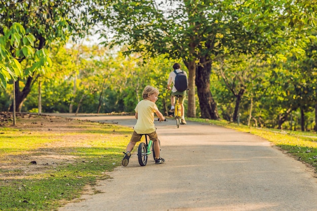 Szczęśliwa rodzina jeździ na rowerach na świeżym powietrzu i uśmiecha się. Ojciec na rowerze i syn na balancebike