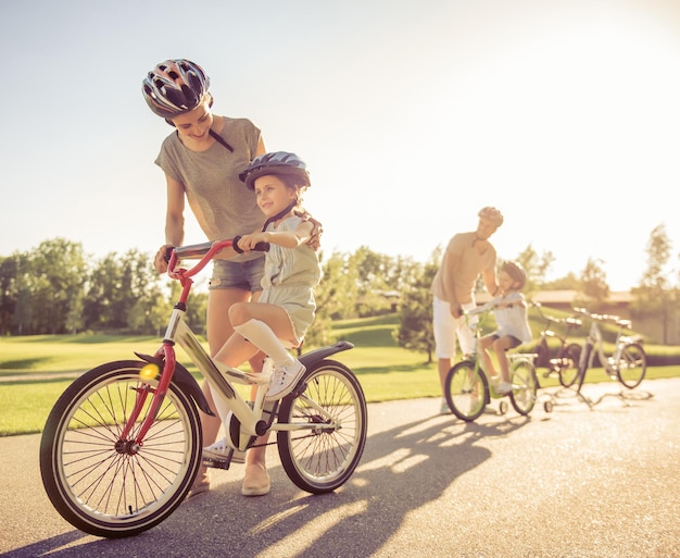 Szczęśliwa rodzina jeździ na rowerach na świeżym powietrzu i uśmiecha się. Rodzice uczą swoje dzieci