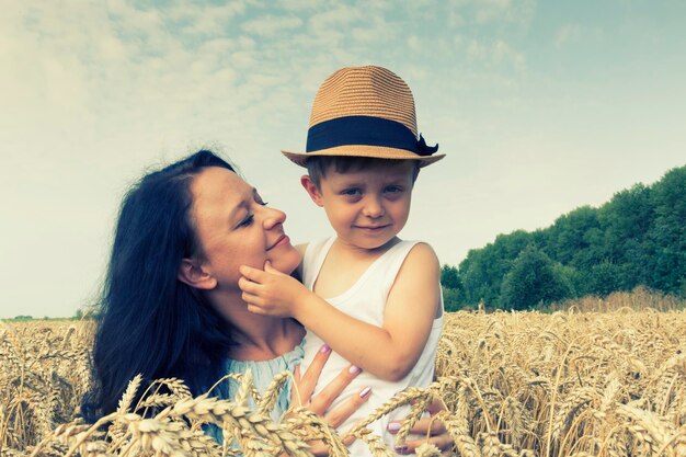 Szczęśliwa rodzina Mama i syn śmieją się i rozmawiają na polu pszenicy Widok z przodu