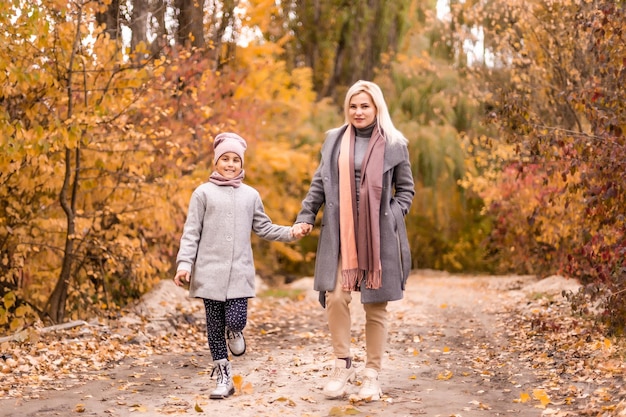 Szczęśliwa rodzina matka i córka dziecka bawią się i śmieją na jesiennym spacerze. Relacje matki i dziecka. Modna mama i córka w stylowym wyglądzie w tych samych kurtkach