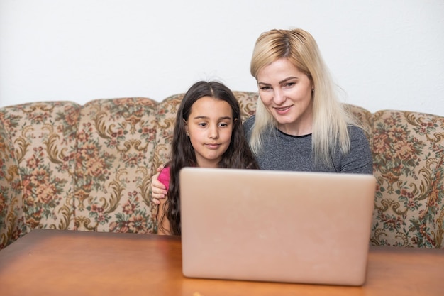 Szczęśliwa rodzina Matka i córka oglądają rozrywkę wideo z technologią komputera przenośnego w salonie cieszą się koncepcją życia w domu