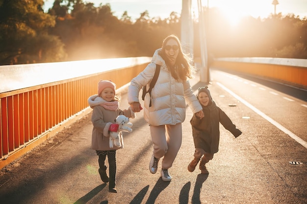 Zdjęcie szczęśliwa rodzina, matka i dwójka dzieci w ciepłych ubraniach, biegające na świeżym powietrzu w sezonie jesiennym. koncepcja wolności