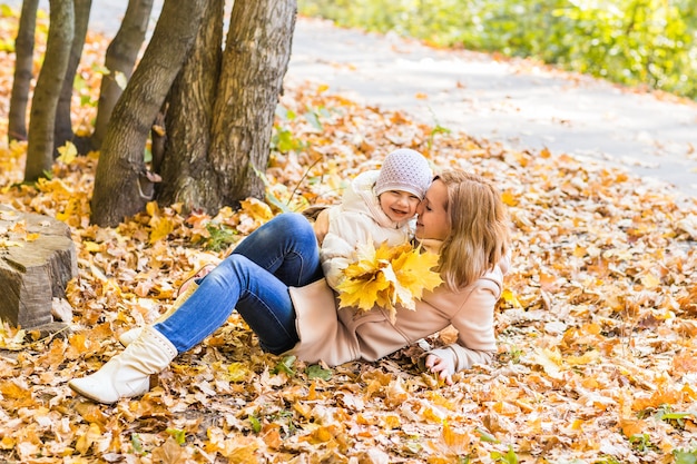 szczęśliwa rodzina matka i dziecko śmieją się z liśćmi w przyrodzie jesienią